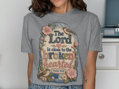 Gray t-shirt with "The Lord is close to the brokenhearted Psalm 34:18" text and floral design.