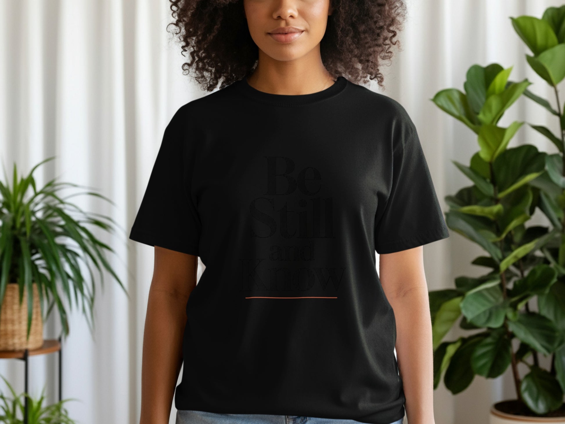 Black t-shirt with "Be Still and Know" text and an orange line.