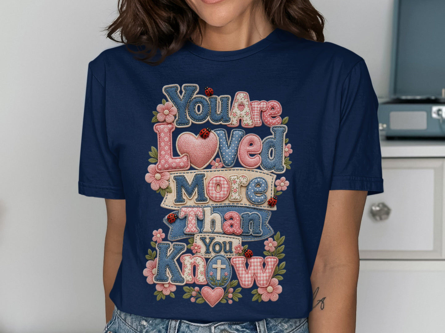 Navy t-shirt with "You Are Loved More Than You Know" text and heart designs.