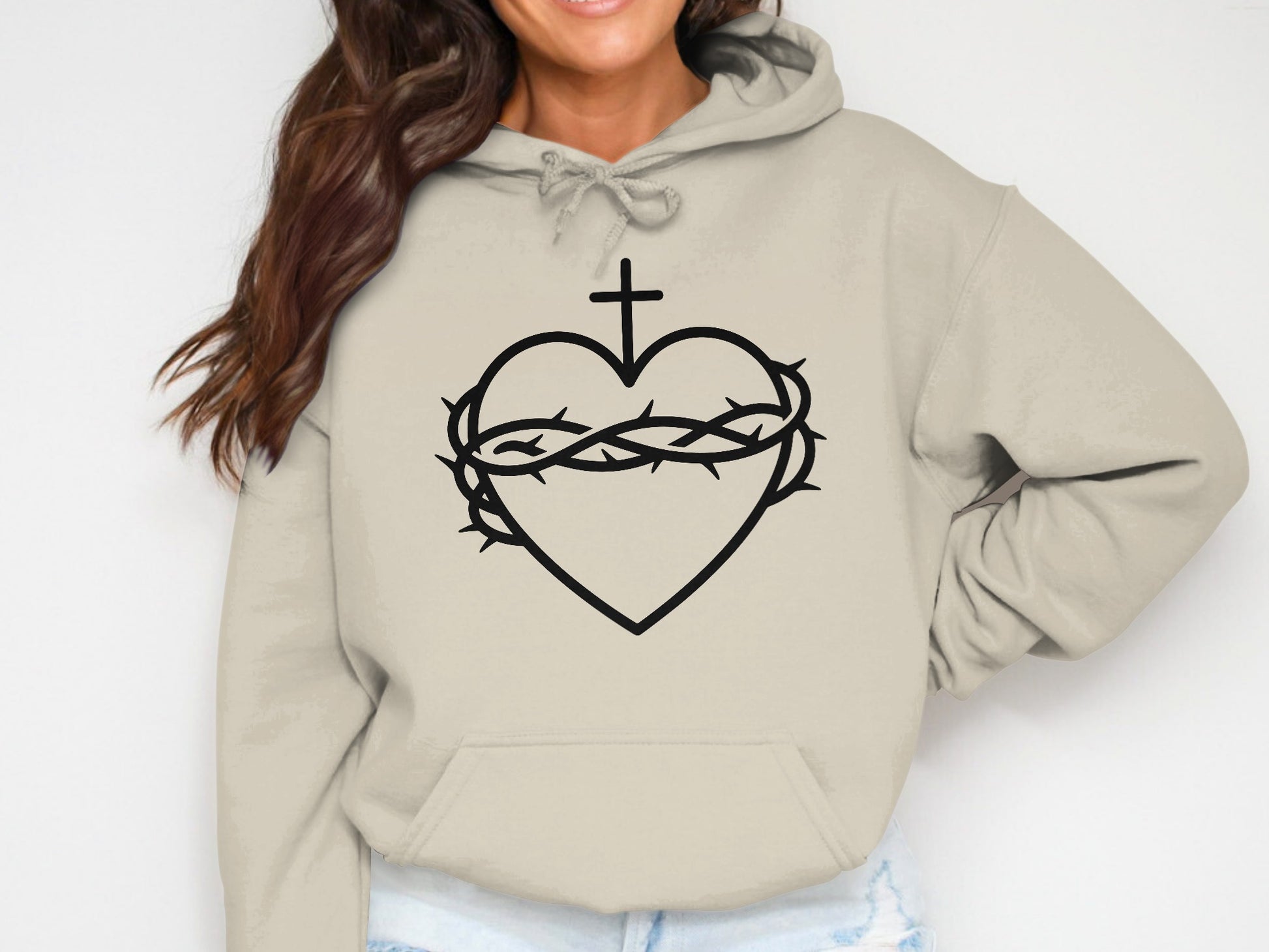 Beige hoodie with black Sacred Heart and crown of thorns graphic.