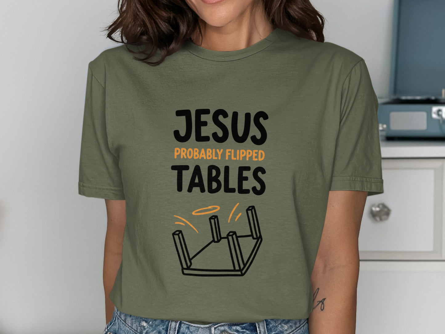 Olive green t-shirt with "Jesus Probably Flipped Tables" and overturned table graphic.