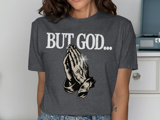 Dark gray t-shirt with "BUT GOD..." and praying hands graphic.