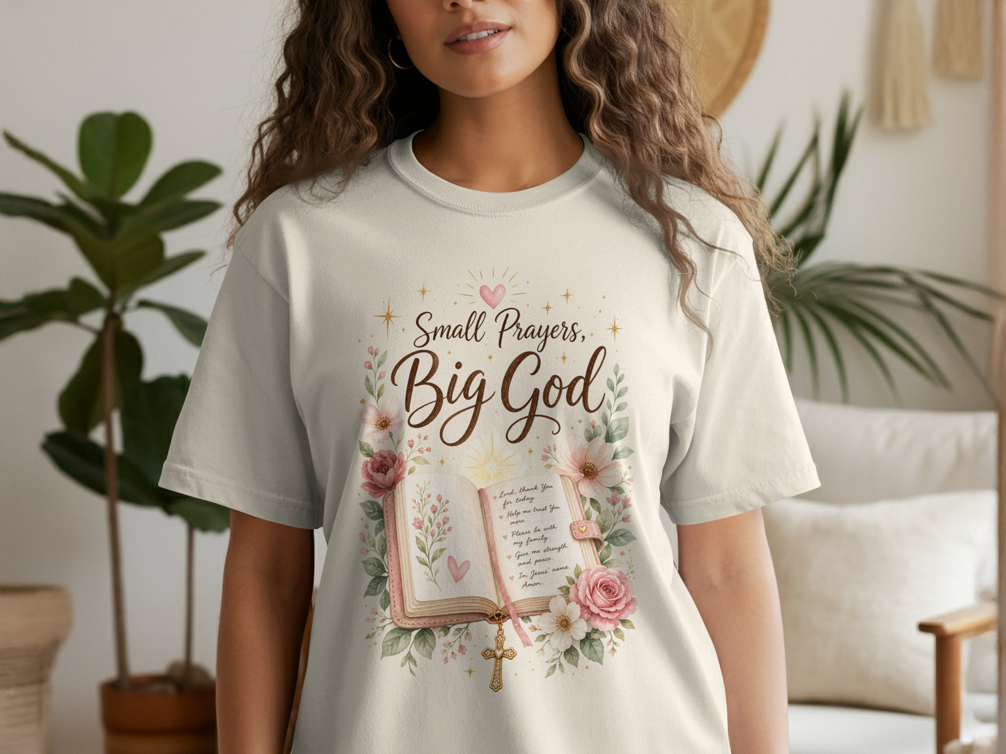 Cream t-shirt with watercolor design of an open book, flowers, a cross, and text.