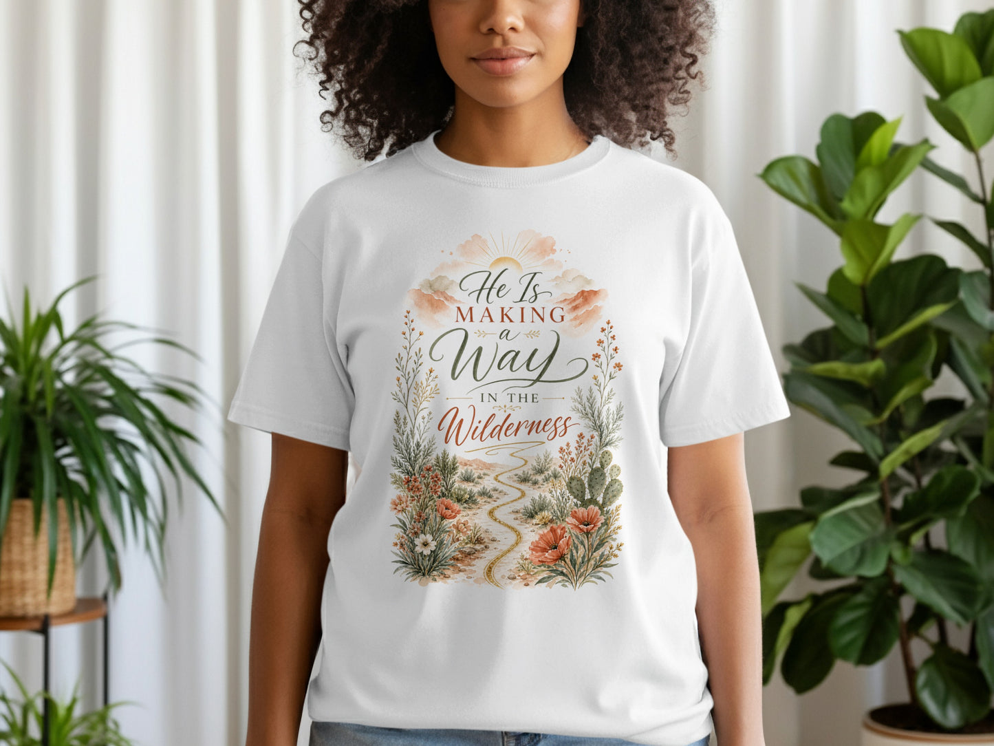 White t-shirt with "He Is Making a Way In The Wilderness" text and desert landscape graphic.
