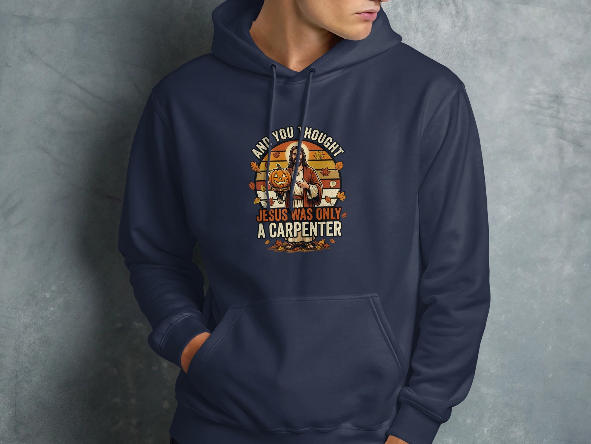 Navy hoodie with "And you thought Jesus was only a carpenter" text and illustration.