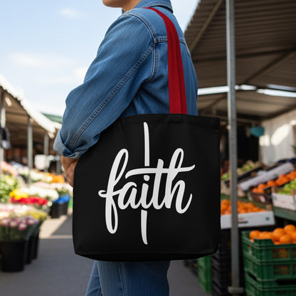 Black tote bag with white "faith" text and red straps, outdoors.
