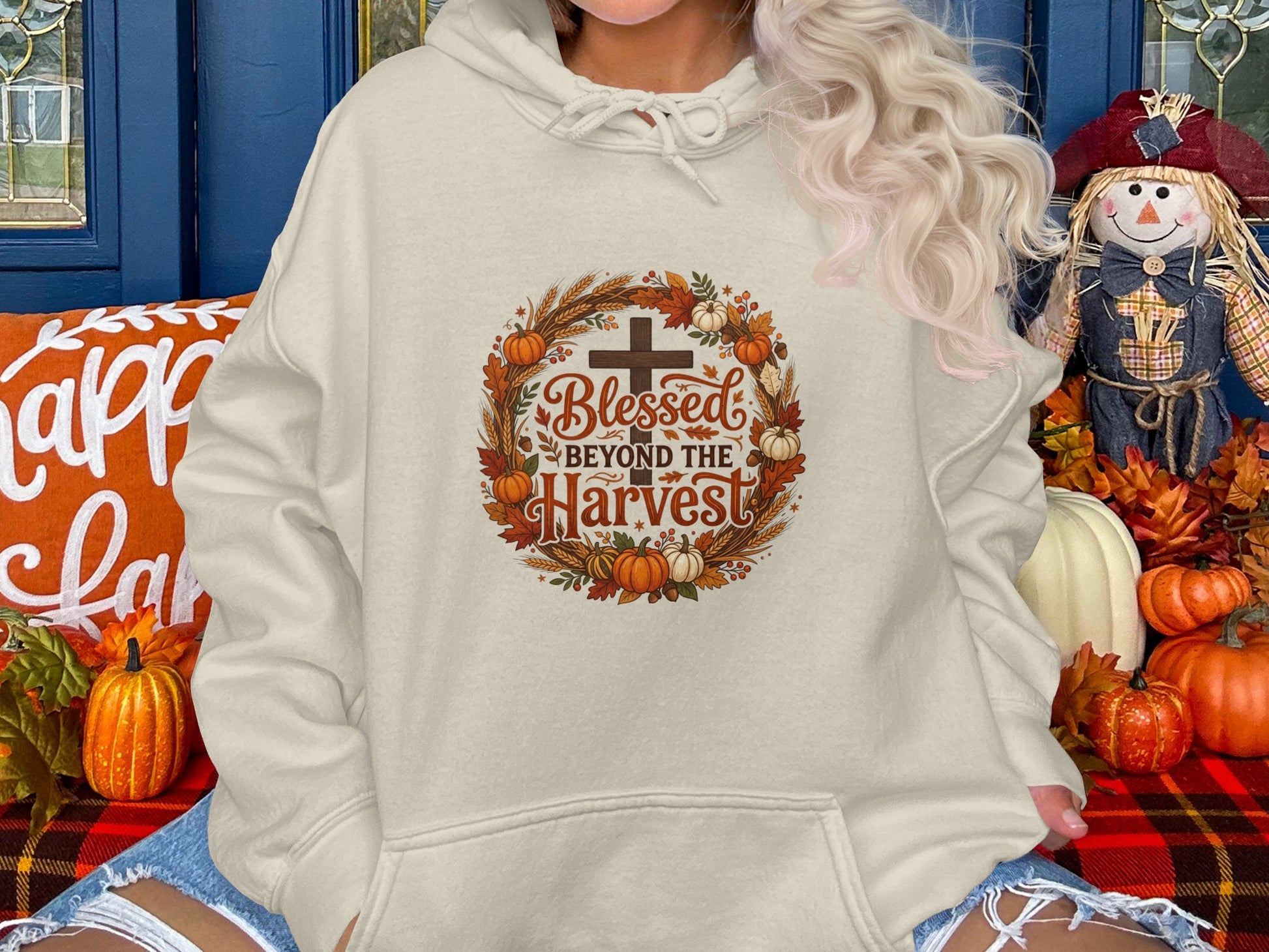 Cream hoodie with "Blessed Beyond the Harvest" circular graphic and autumn motifs.