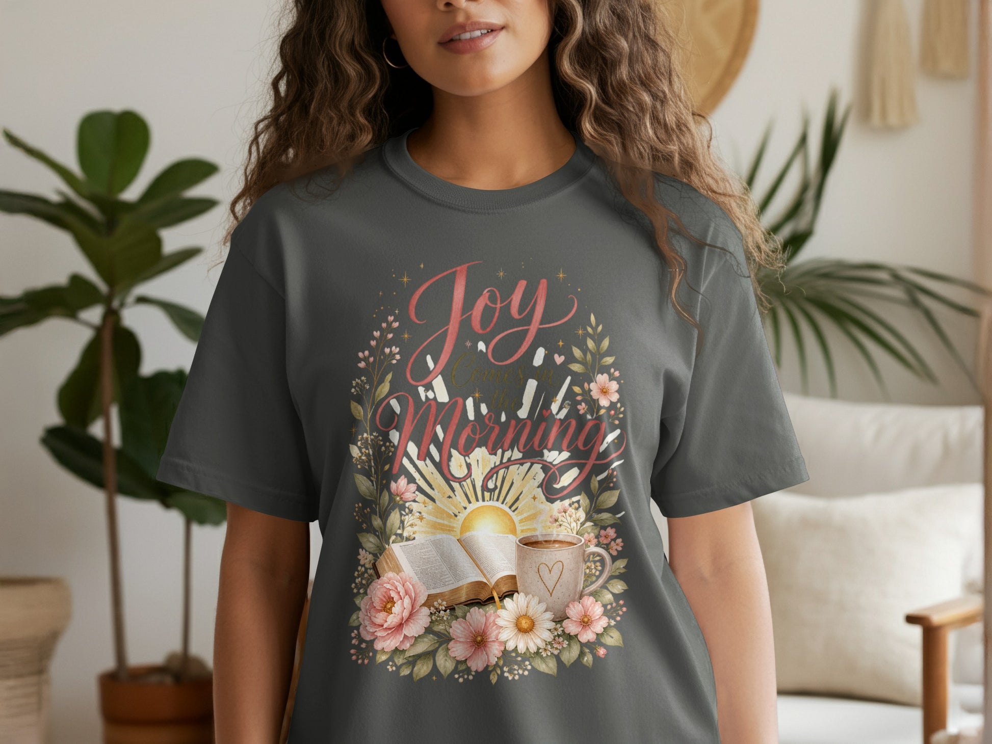 Dark gray t-shirt with "Joy Comes in the Morning" text, open book, coffee mug, and flowers.