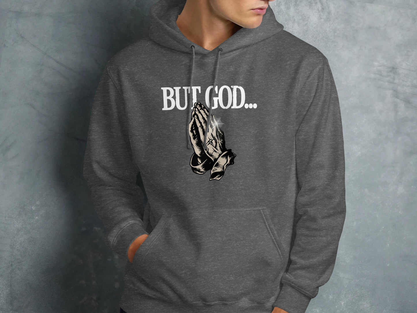 Dark gray hoodie with "BUT GOD..." text and praying hands graphic.