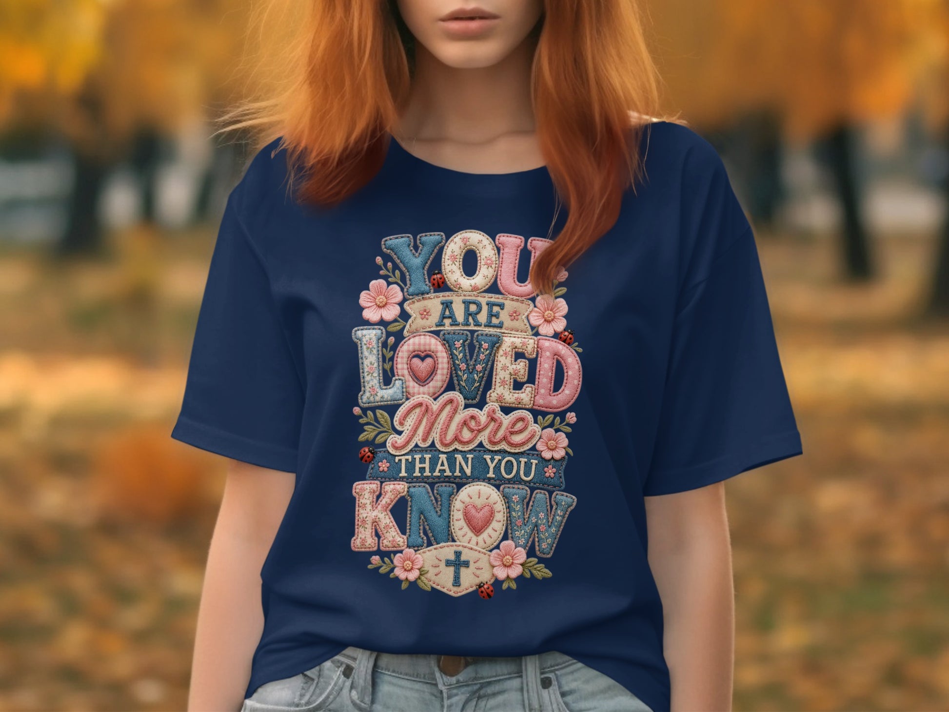 Navy t-shirt with "You Are Loved More Than You Know" text and floral designs.