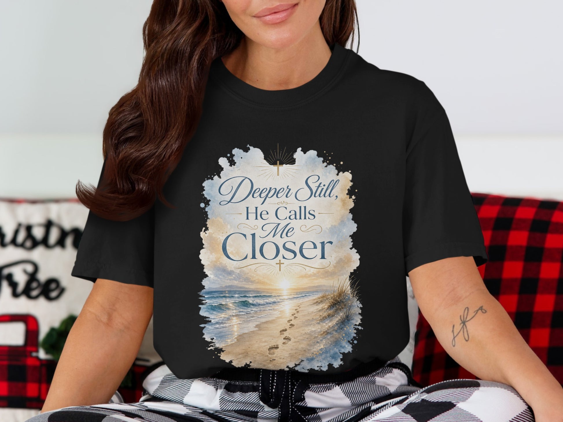 Black t-shirt with "Deeper Still, He Calls Me Closer" text and beach sunset design.