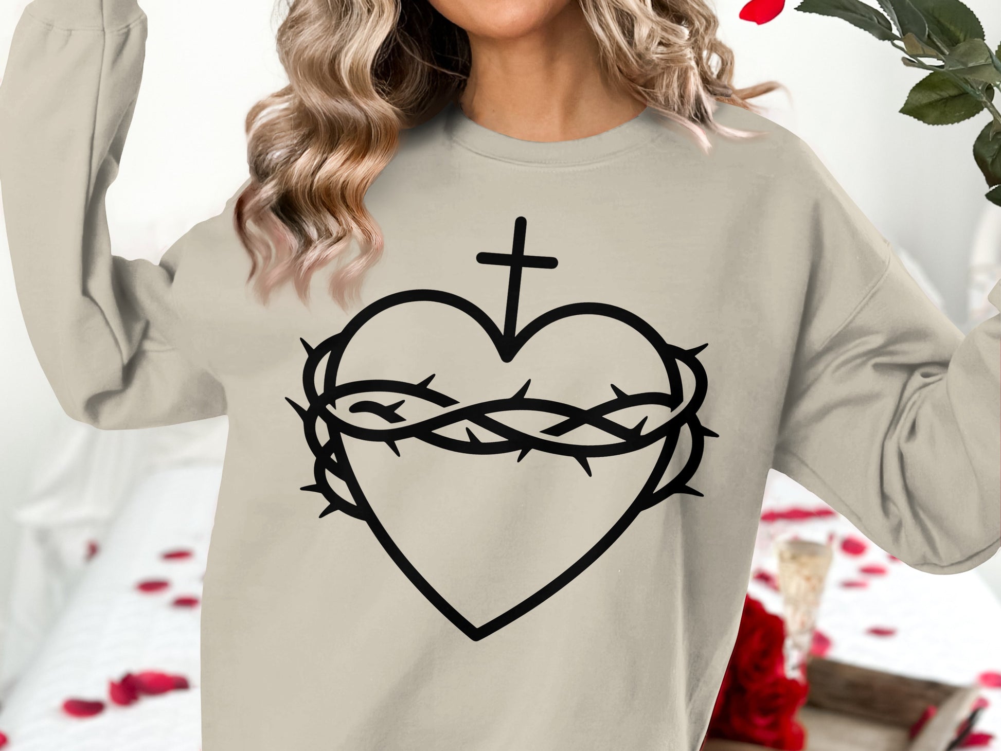 Cream sweatshirt with a black graphic of a heart, crown of thorns, and cross.