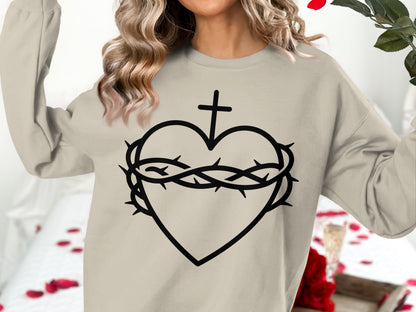 Cream sweatshirt with a black graphic of a heart, crown of thorns, and cross.