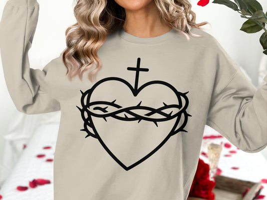 Cream sweatshirt with a black graphic of a heart, crown of thorns, and cross.