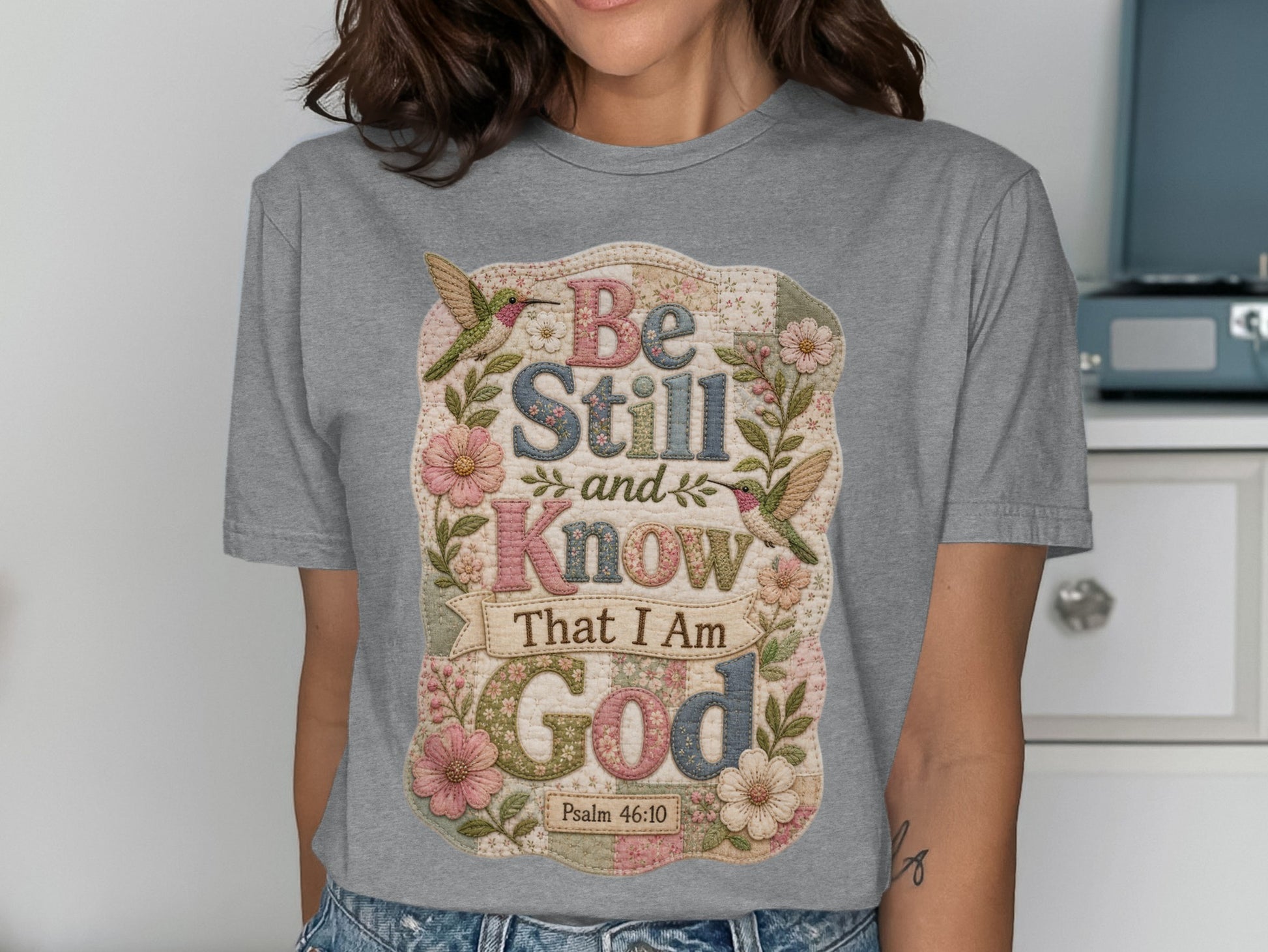 Grey t-shirt with floral design and "Be Still and Know That I Am God" text.