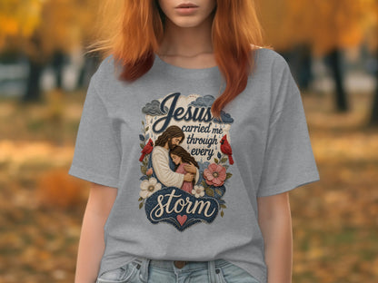 Grey t-shirt with Jesus embracing a woman, with text "Jesus carried me through every storm".