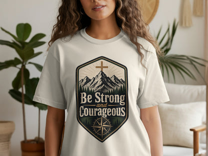 Light cream t-shirt with a shield design featuring mountains, cross, and the text "Be Strong and Courageous."