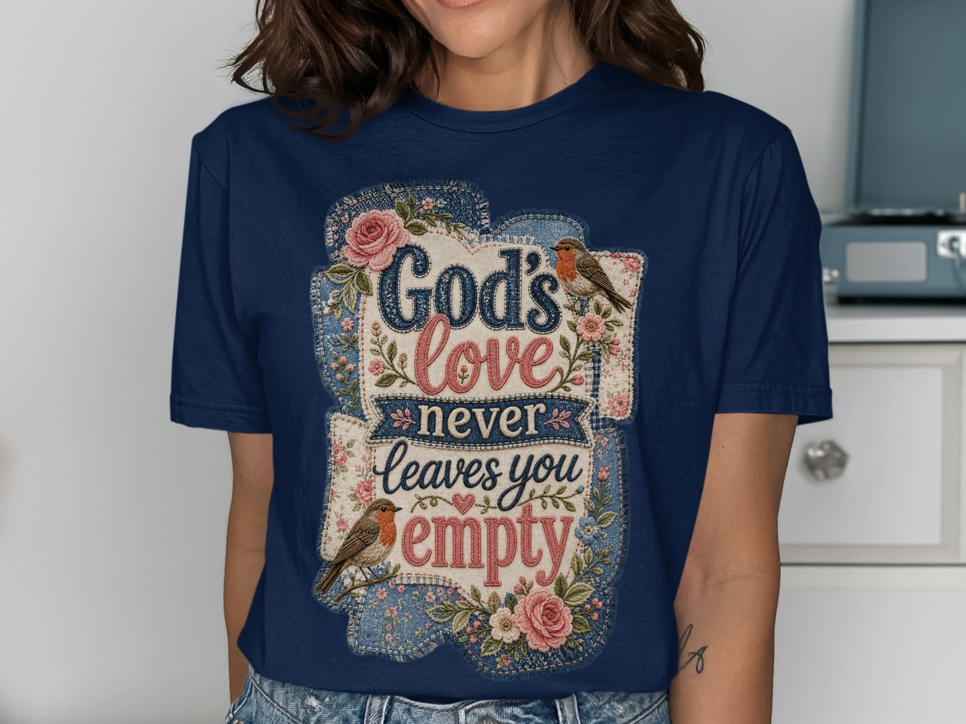 Navy t-shirt with "God's love never leaves you empty" text and floral robin designs.