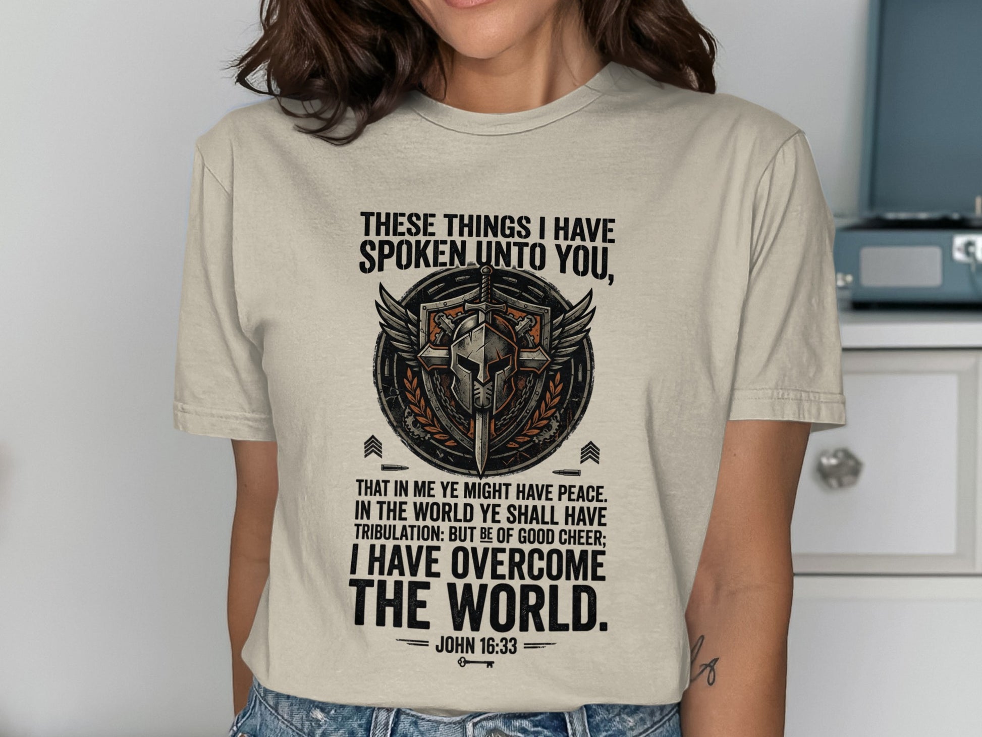 T-shirt with shield, wings, and biblical quote "I have overcome the world."