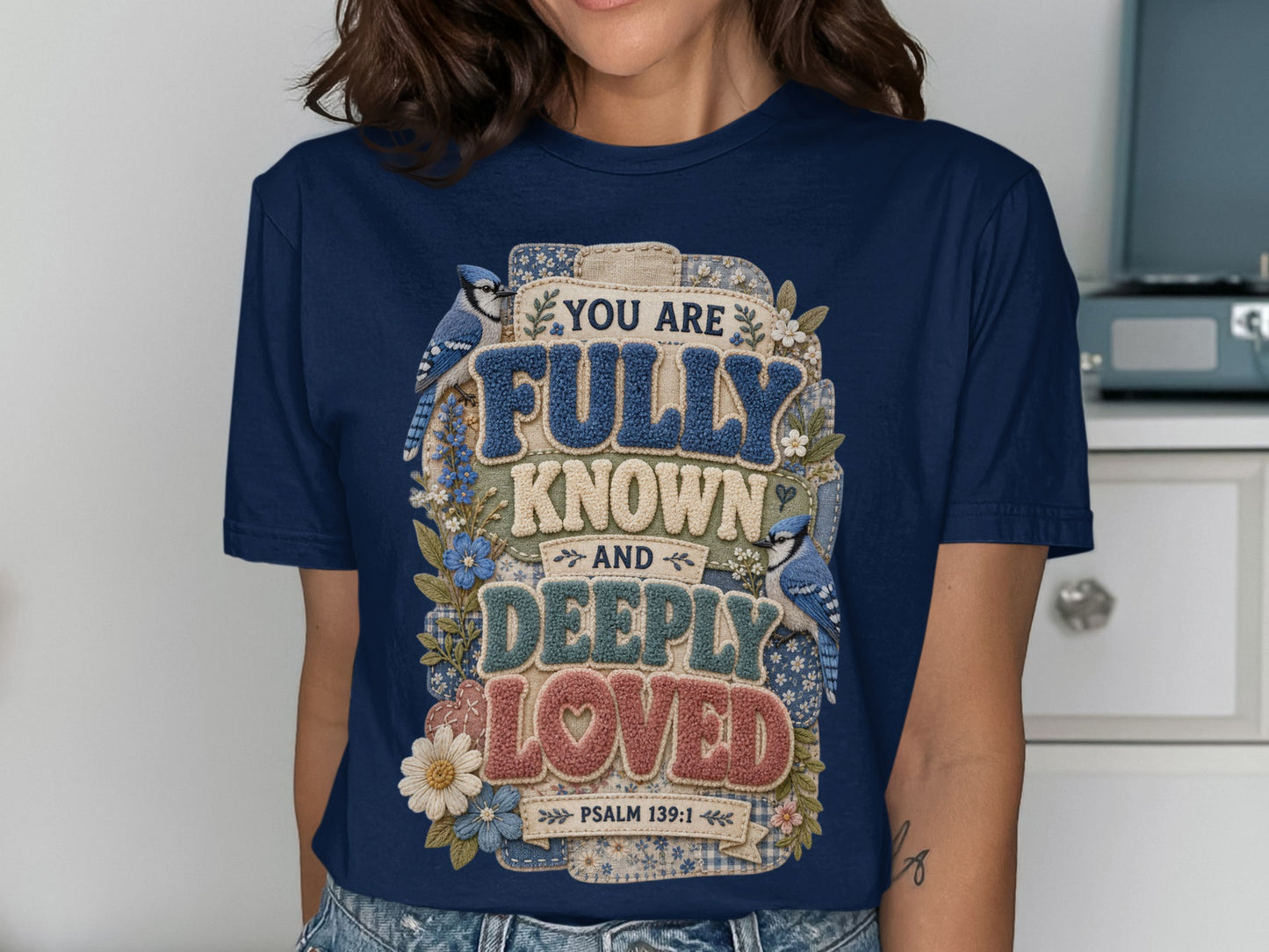 Navy t-shirt with "You are fully known and deeply loved" text, bluebirds, and flowers.