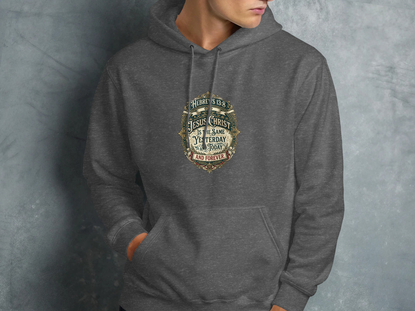 Dark grey hoodie with religious text about Jesus Christ in ornate circular design.