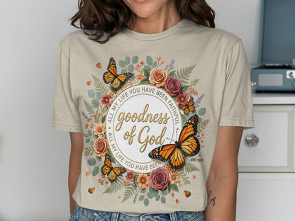 White t-shirt with floral wreath, butterflies, and text "goodness of God"