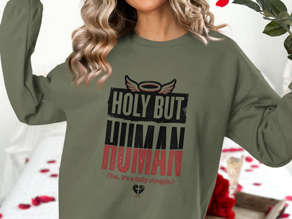 Green sweatshirt with "HOLY BUT HUMAN" text and a halo.