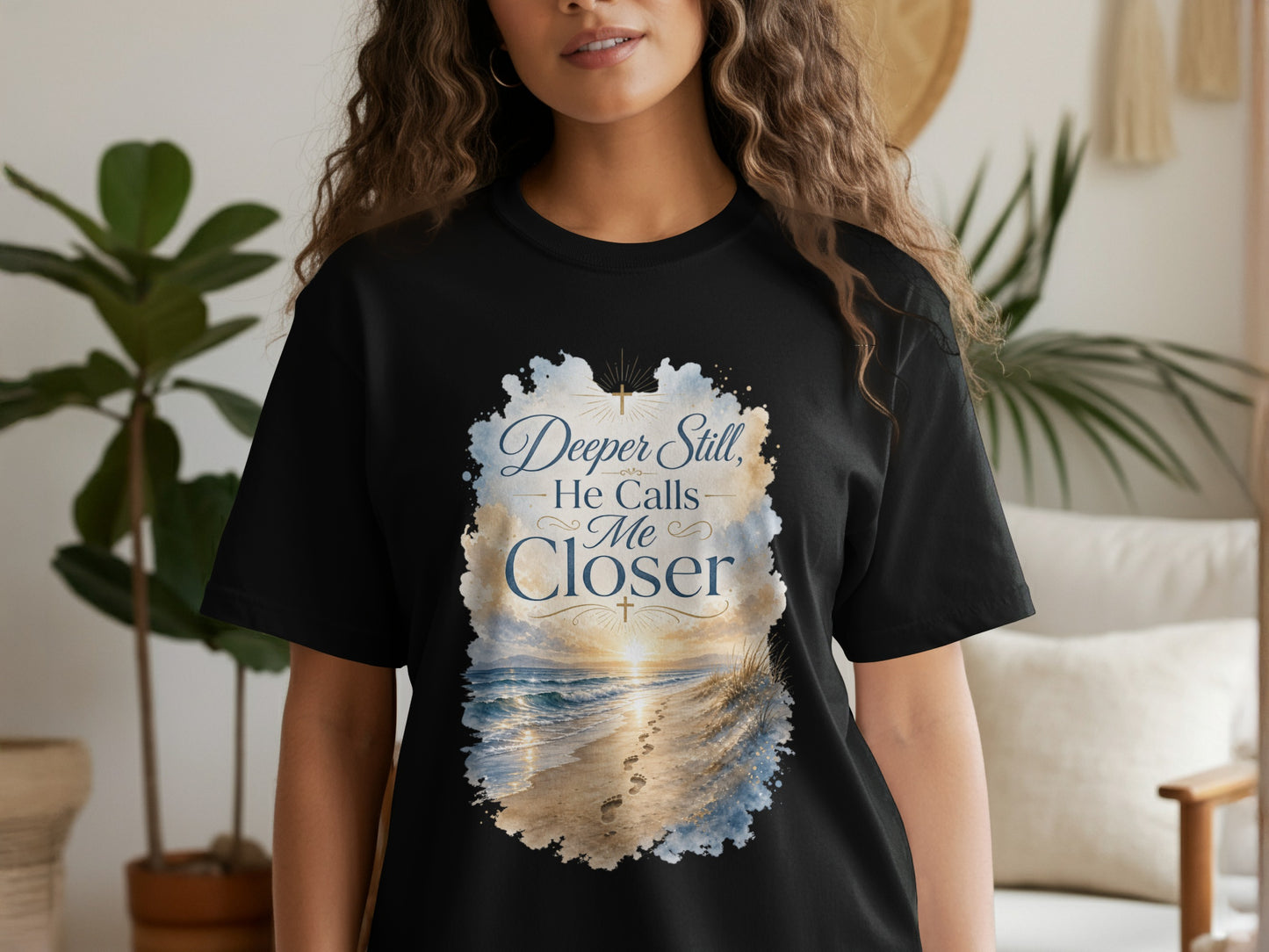 Black t-shirt with "Deeper Still, He Calls Me Closer" and beach scene.