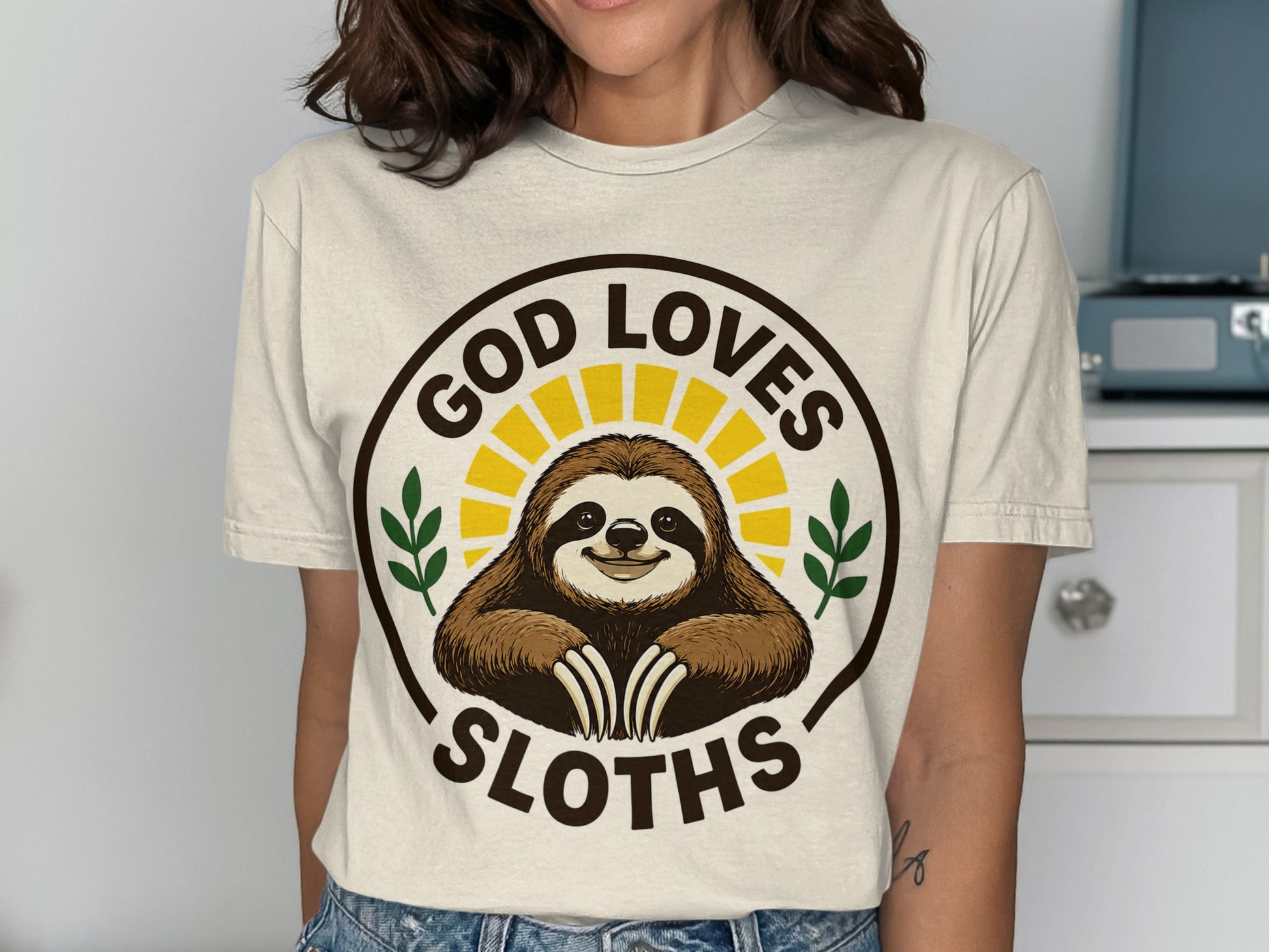 T-shirt with a smiling sloth in a sunburst circle, saying "God Loves Sloths".