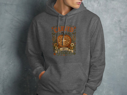 Dark gray hoodie with orange "Carried by Grace" text and floral pumpkin design.