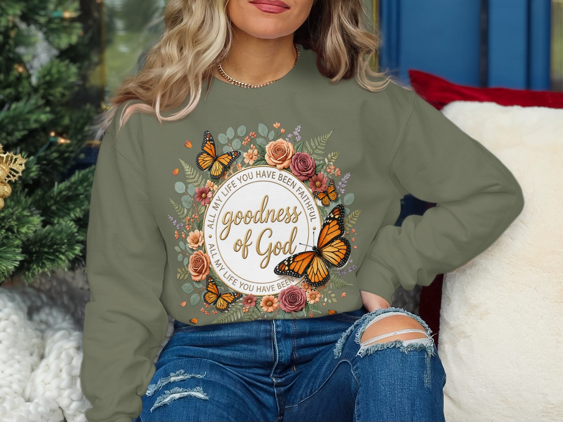 Olive green sweatshirt with floral and butterfly graphic and "goodness of God" text.