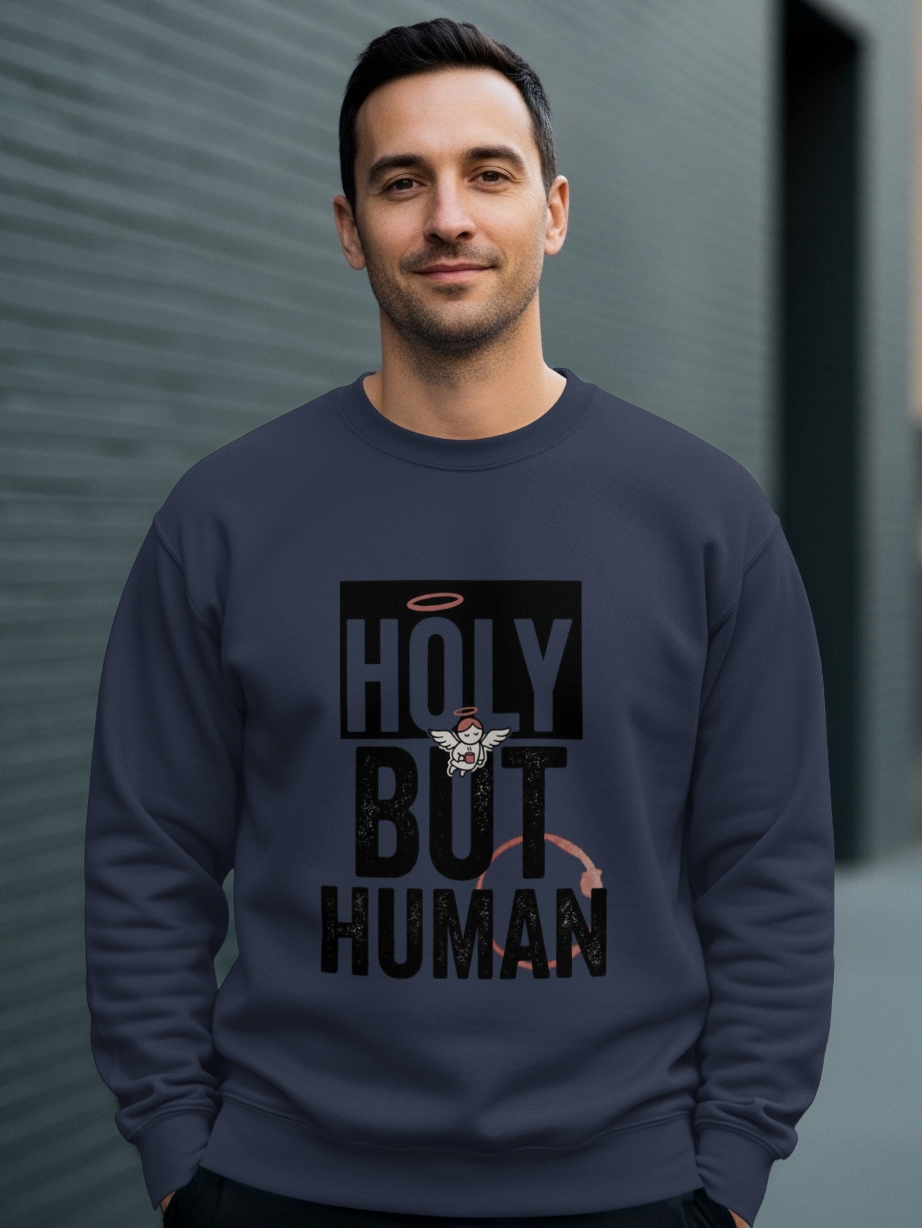 Man wearing navy sweatshirt with "HOLY BUT HUMAN" text and halo graphic.