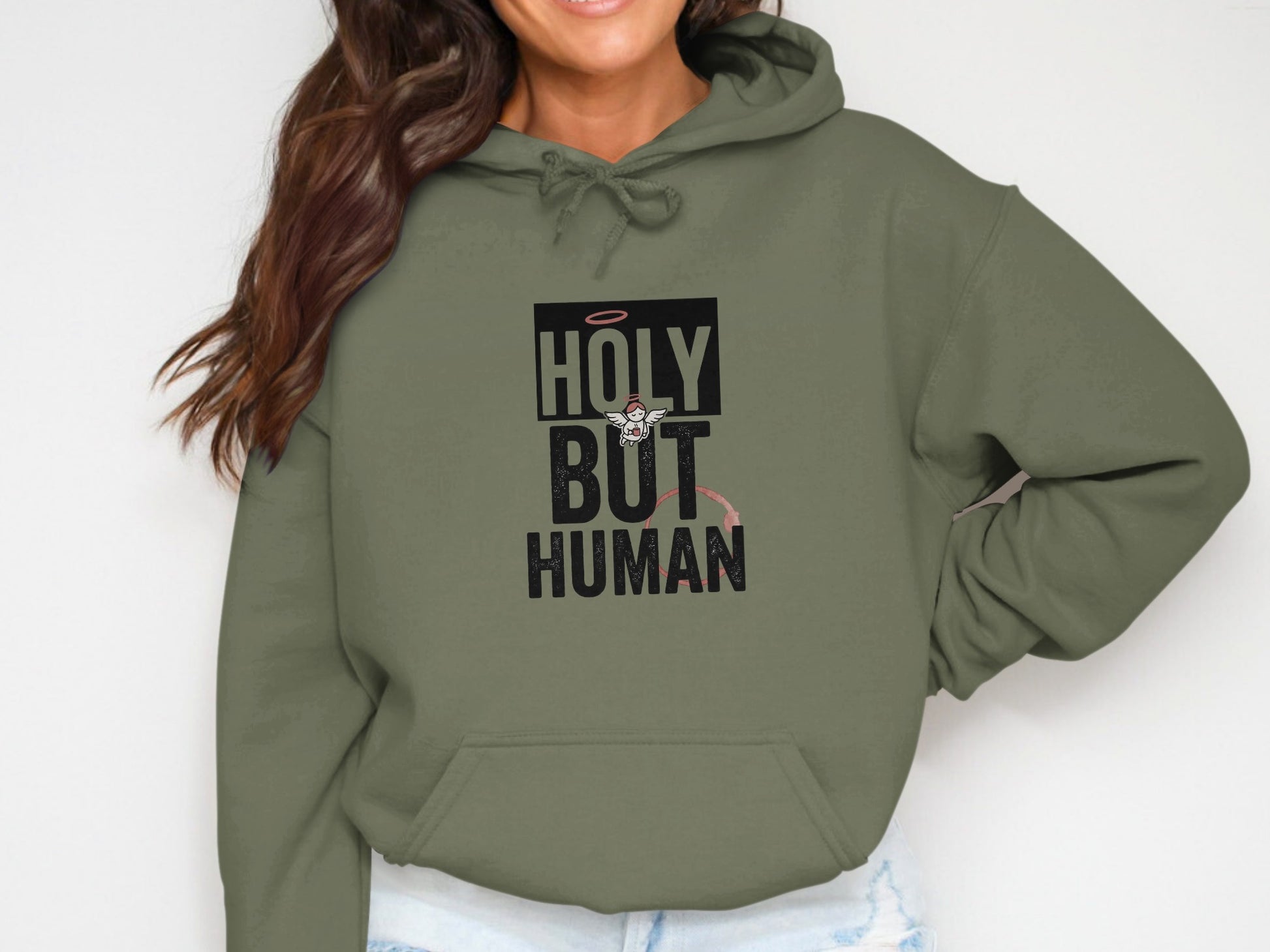 Olive green hoodie with "HOLY BUT HUMAN" text and angelic illustration.