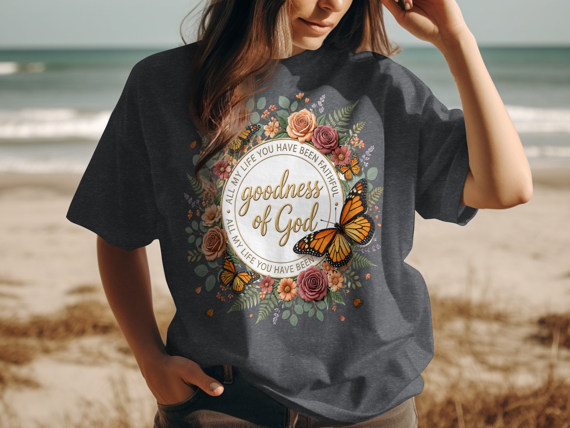 Dark gray t-shirt with floral and butterfly design, featuring text "goodness of God".