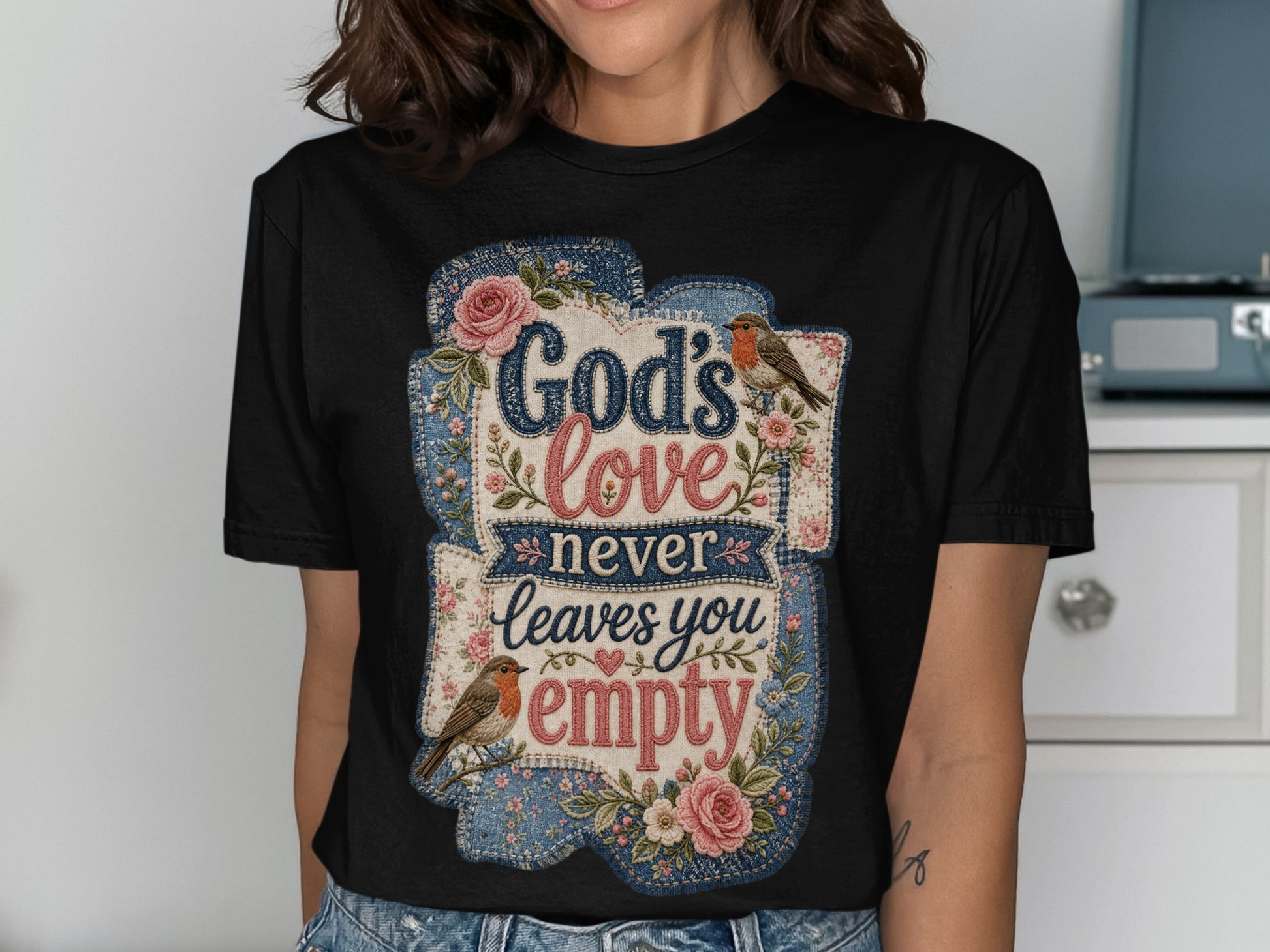 Black t-shirt with "God's love never leaves you empty" text and floral accents.