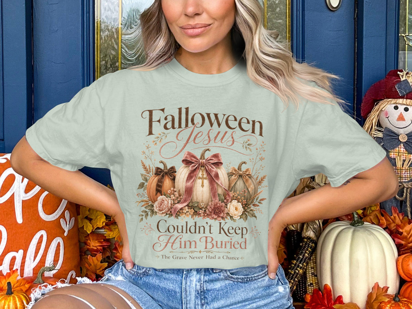 Light green t-shirt with "Falloween Jesus Couldn't Keep Him Buried" text and pumpkins.
