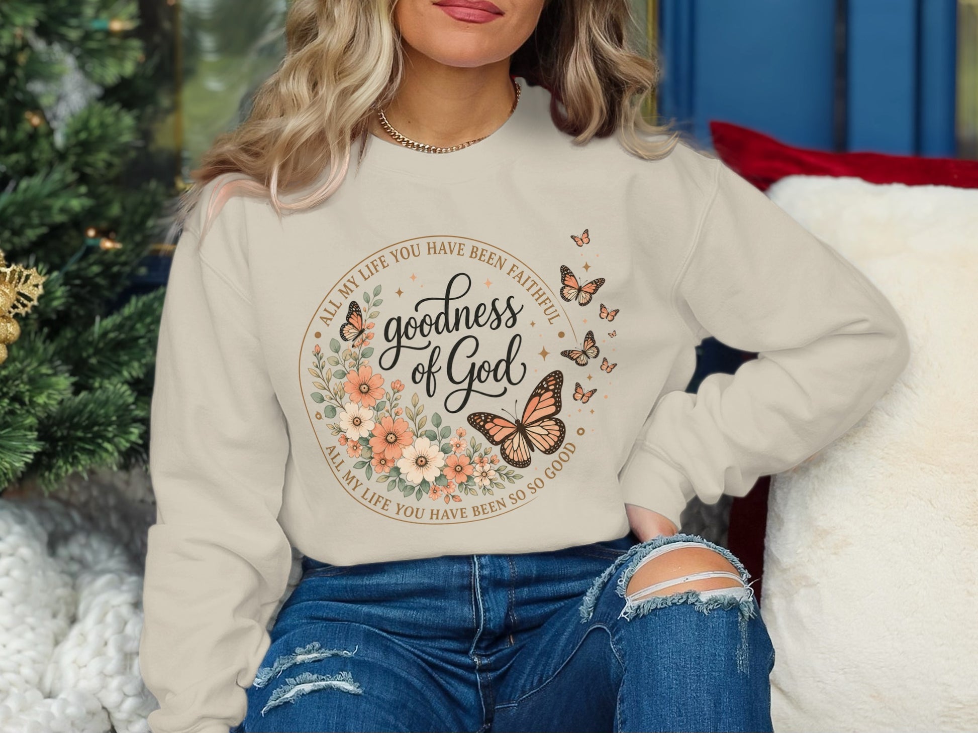 Cream sweatshirt with floral and butterfly graphic and "goodness of God" text.