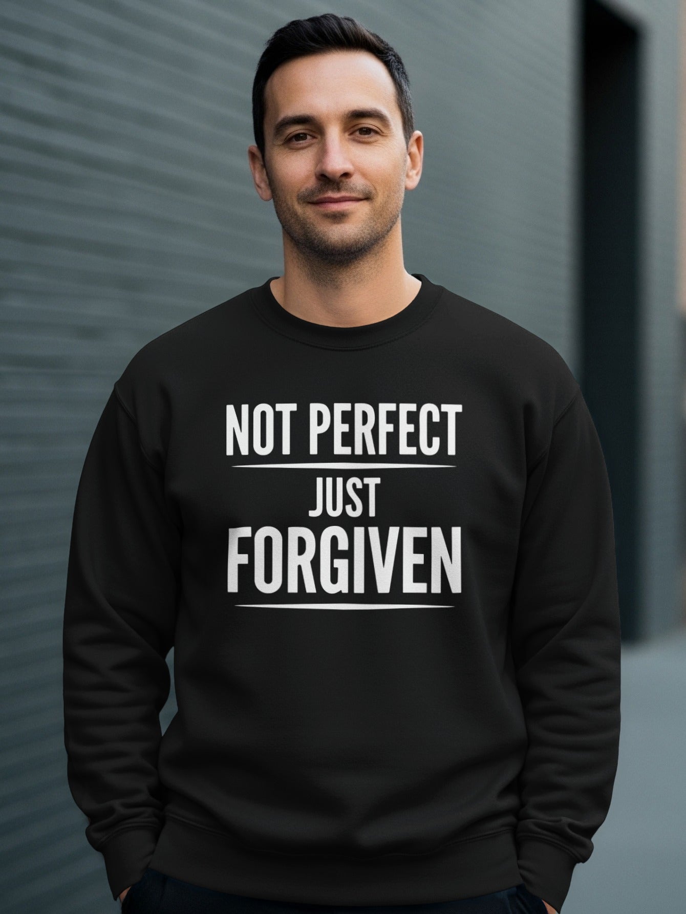 Black sweatshirt with white text "NOT PERFECT JUST FORGIVEN" worn by a man.