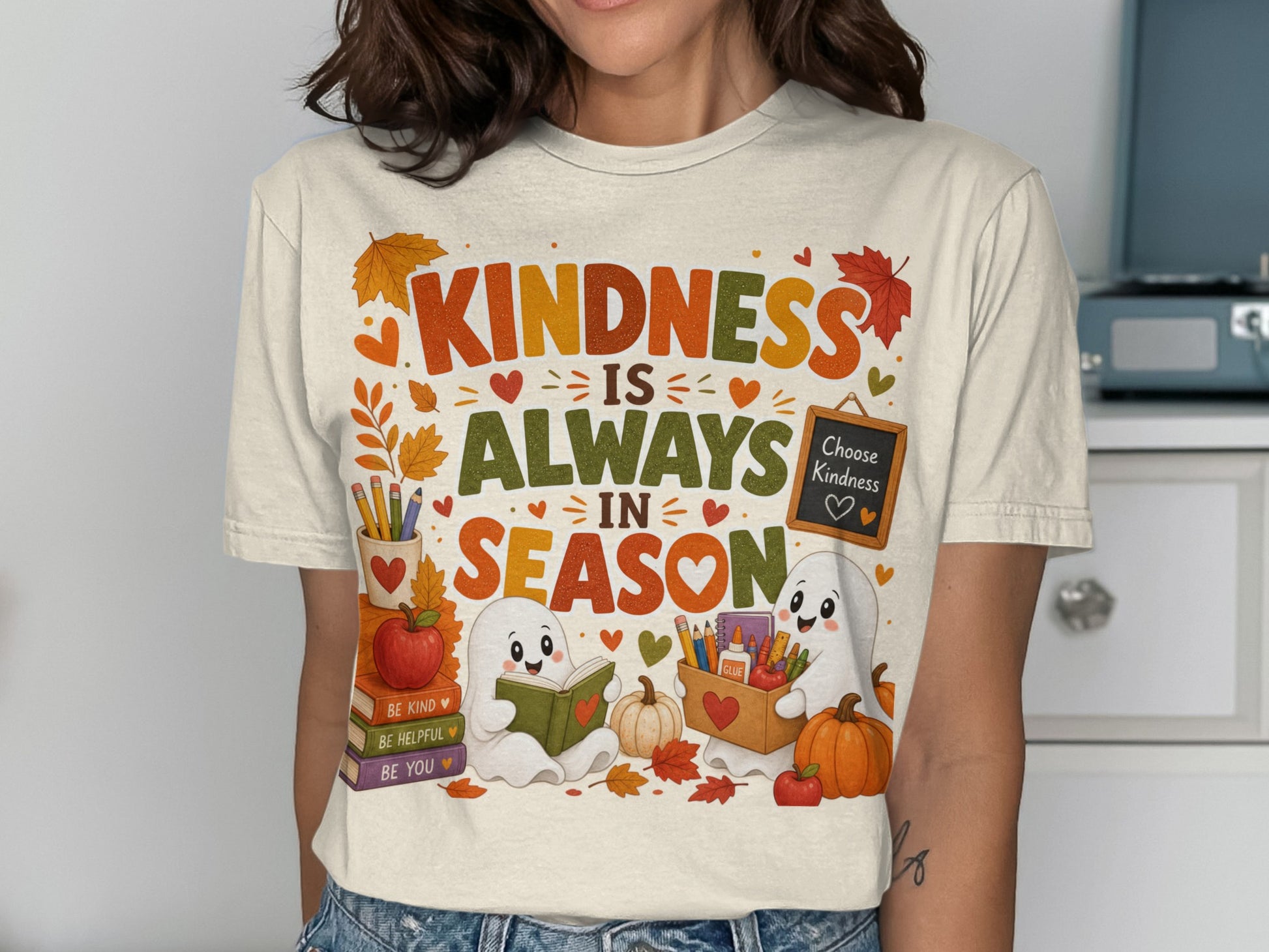 T-shirt graphic: "Kindness Is Always In Season" with cute ghosts, books, and fall leaves.