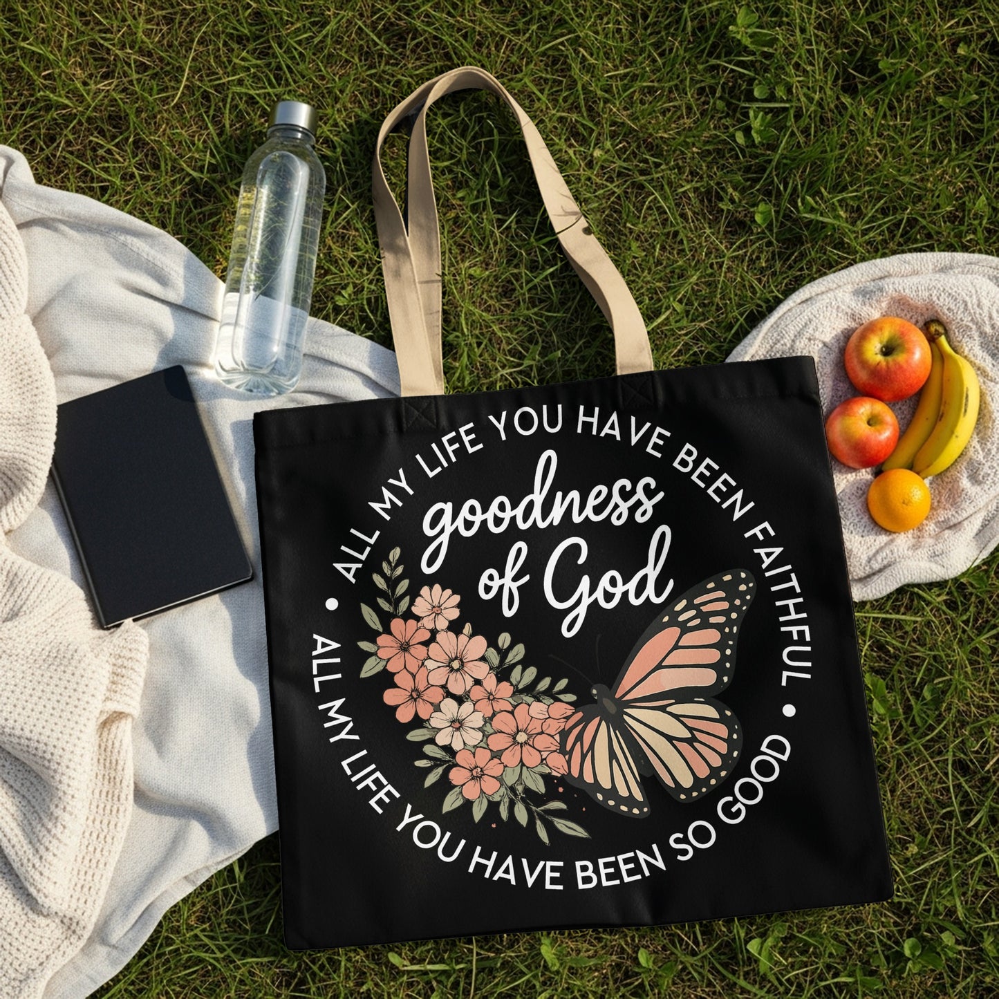 Black tote bag with "goodness of God" text, flowers, and butterfly.