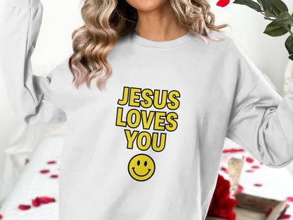 White sweatshirt with "JESUS LOVES YOU" in yellow text and a smiley face.