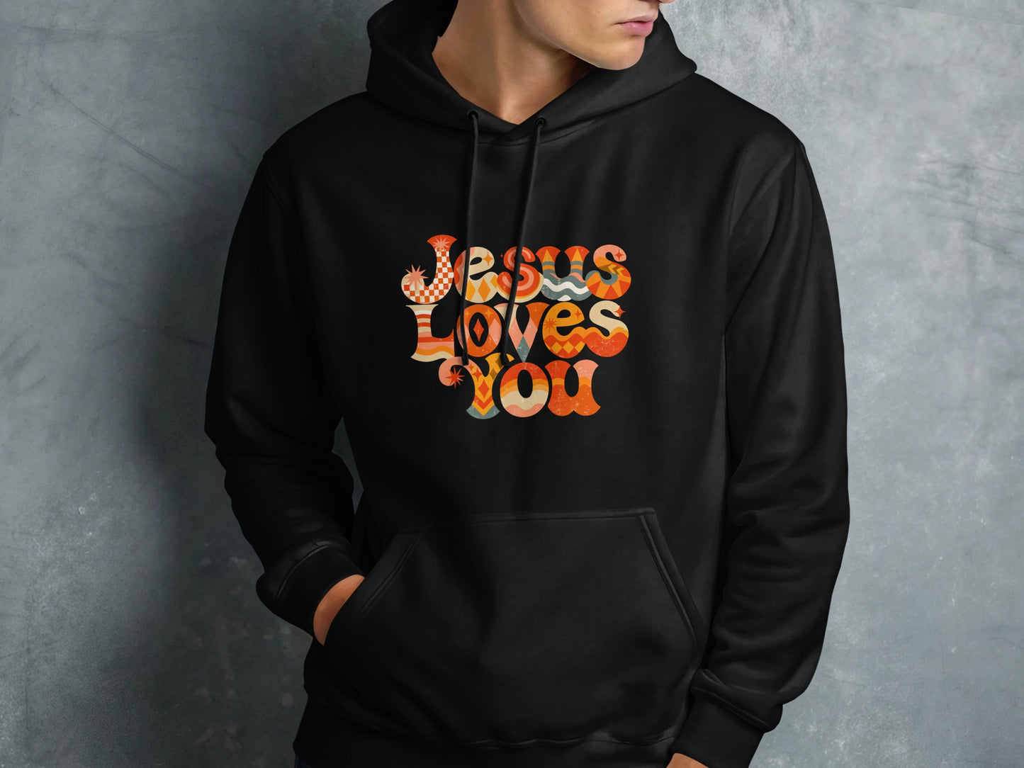 Black hoodie with "Jesus Loves You" text in colorful retro font.