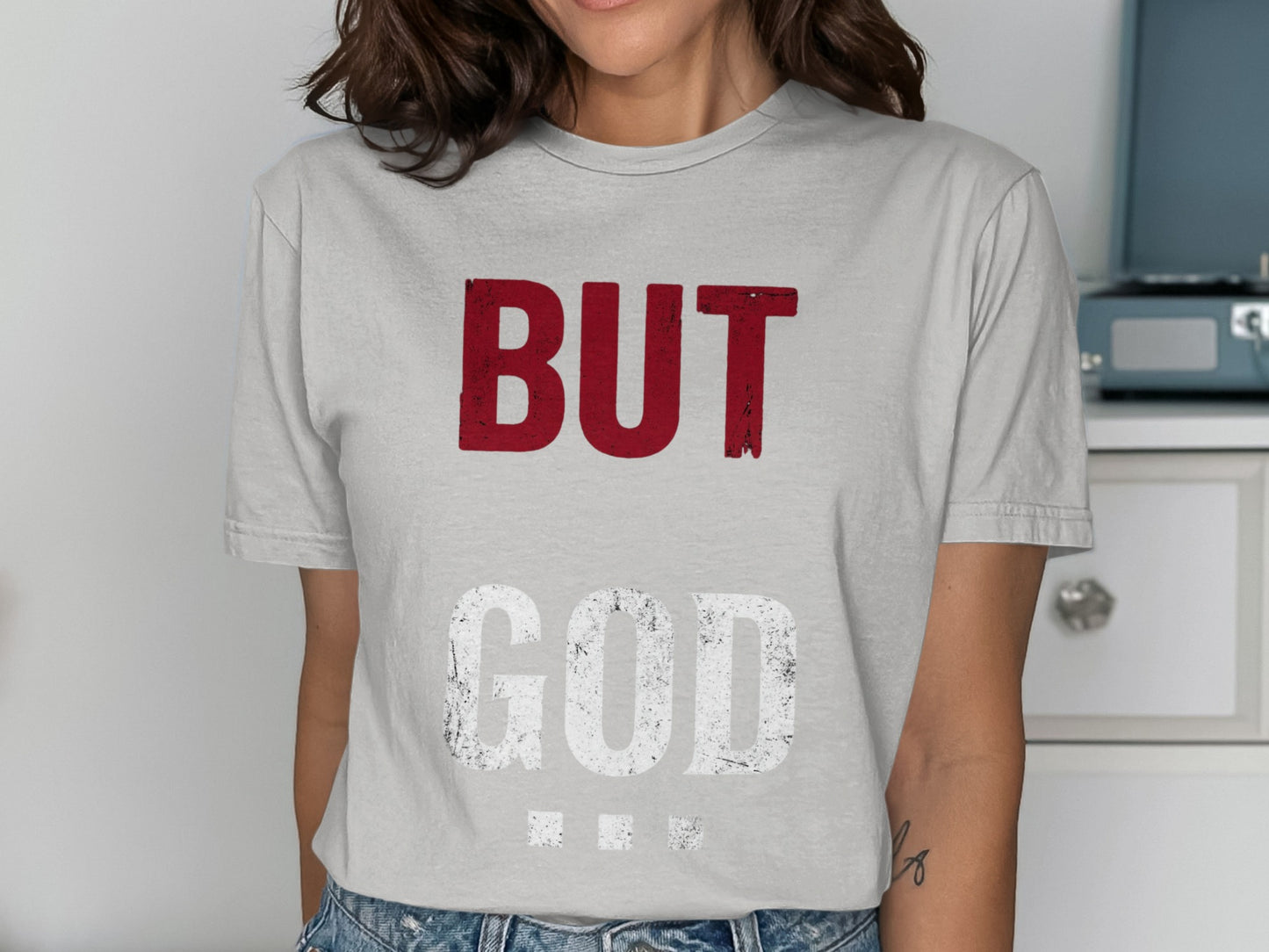 Woman wearing a gray t-shirt with "BUT GOD" text in white and red.