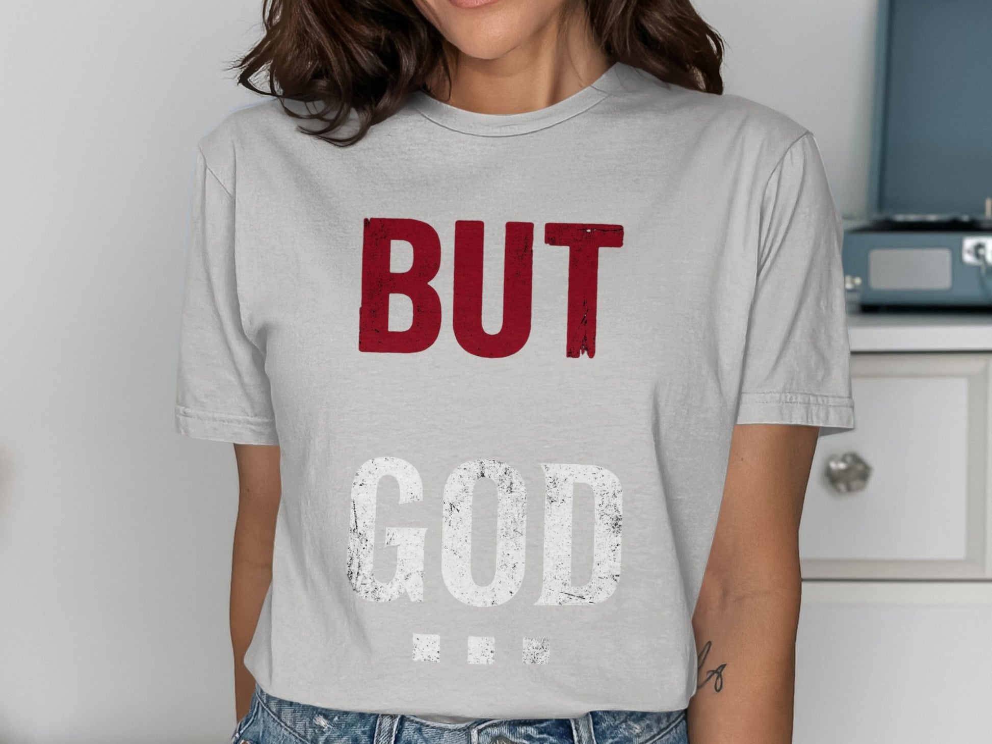 Woman wearing a gray t-shirt with "BUT GOD" text in white and red.
