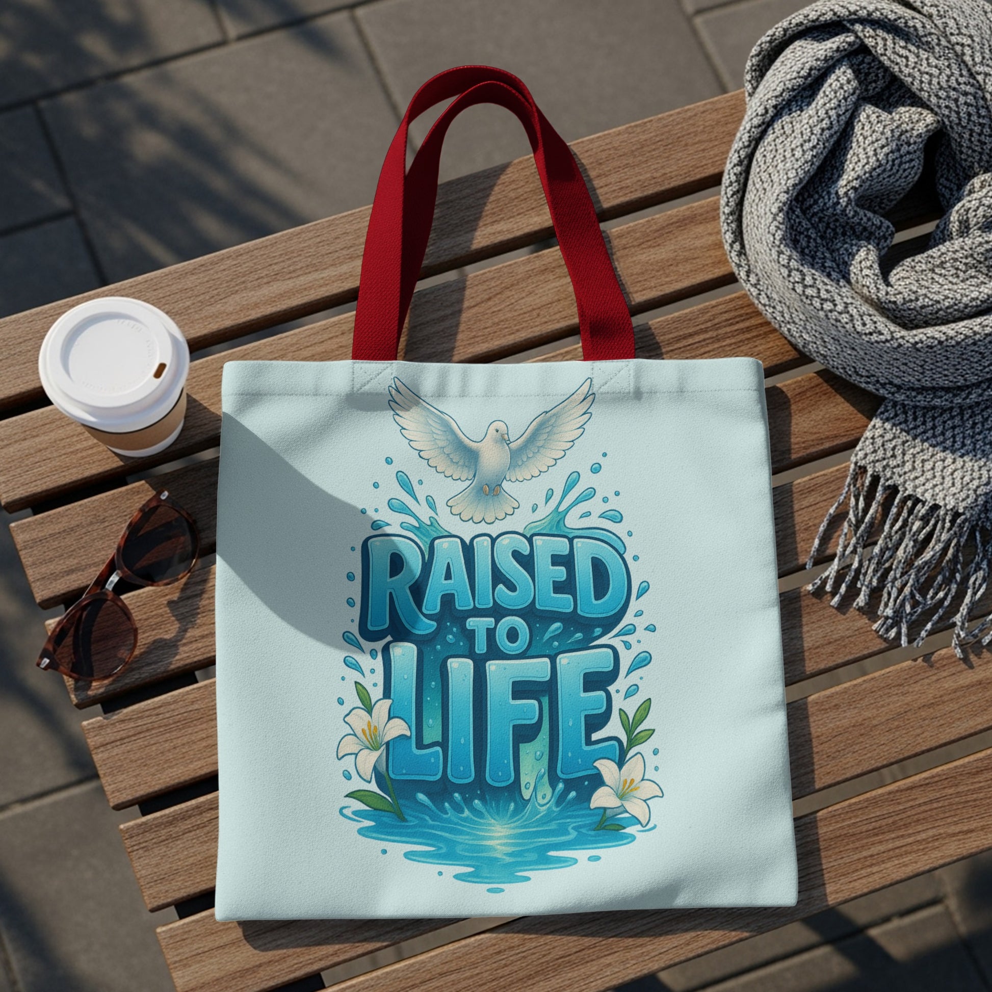 Light blue tote bag with "RAISED TO LIFE" text, dove, and lilies.