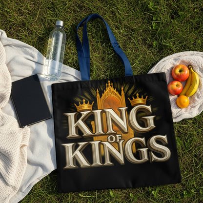 Black tote bag with "KING OF KINGS" text and crown graphic, on grass.