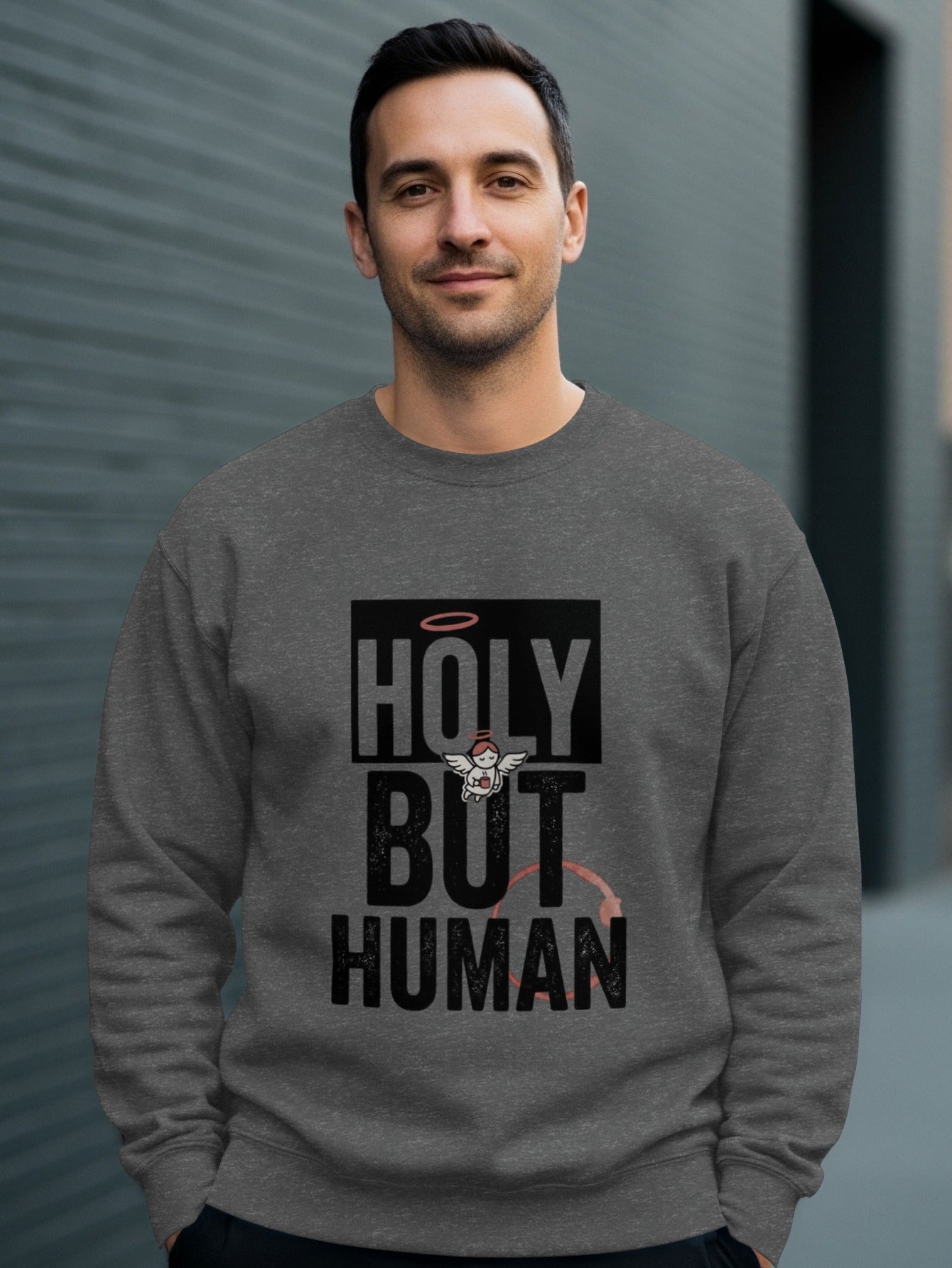 Man wearing a gray sweatshirt with "HOLY BUT HUMAN" text and cupid graphic.