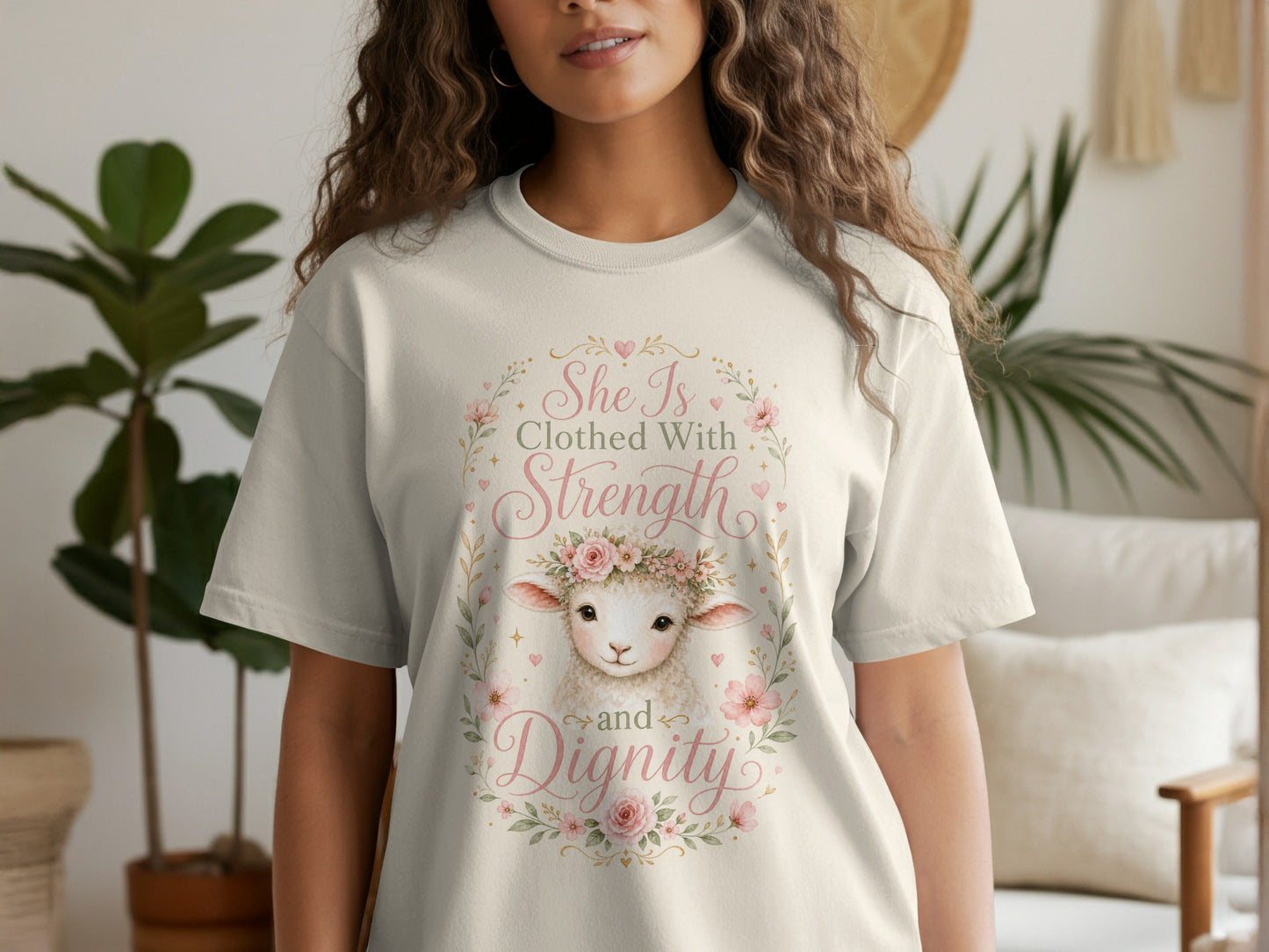 Cream t-shirt with a watercolor sheep wearing a floral crown and text "She Is Clothed With Strength and Dignity."