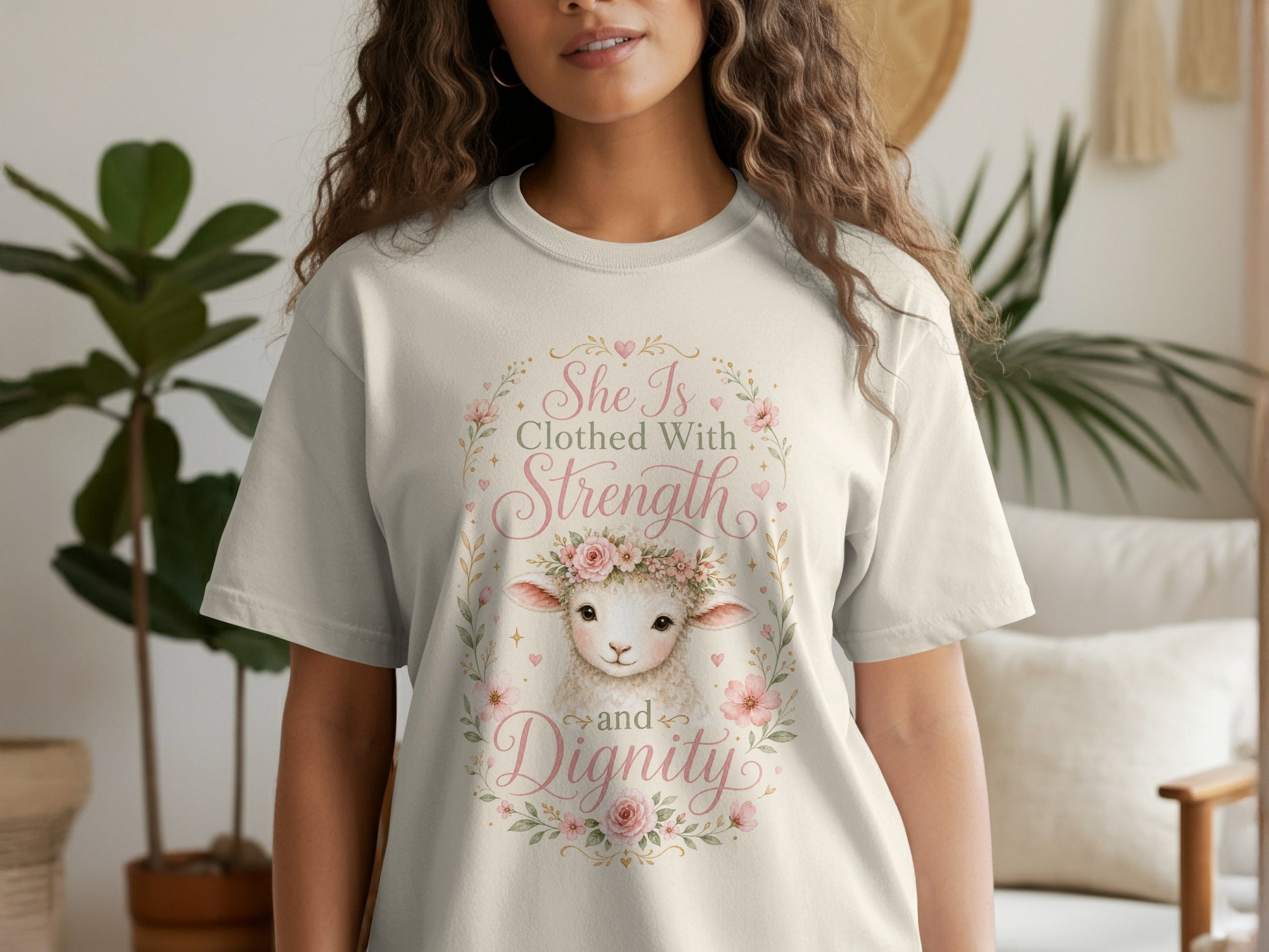 Cream t-shirt with a watercolor sheep wearing a floral crown and text "She Is Clothed With Strength and Dignity."