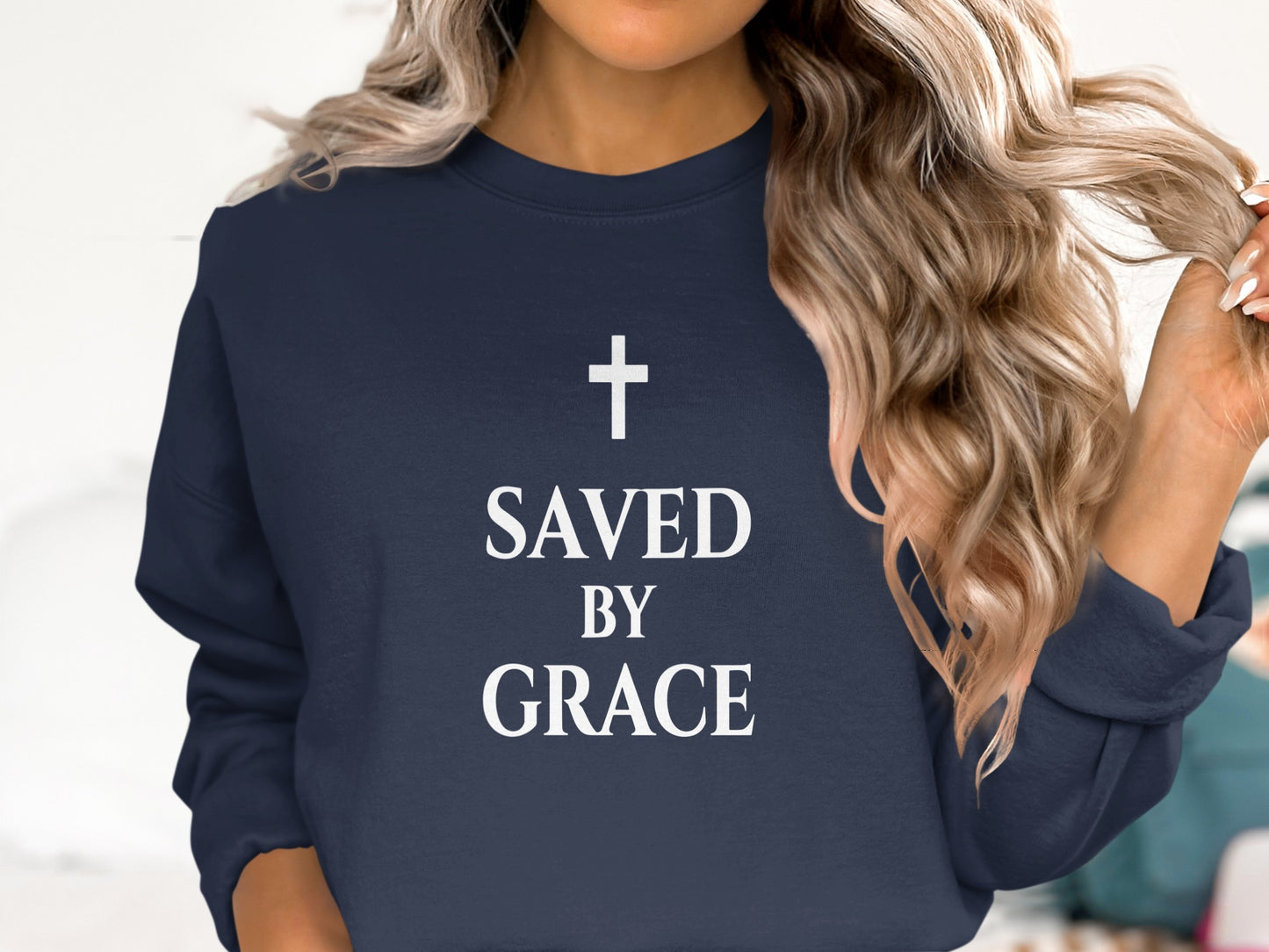 Navy sweatshirt with white text "SAVED BY GRACE" and a cross.